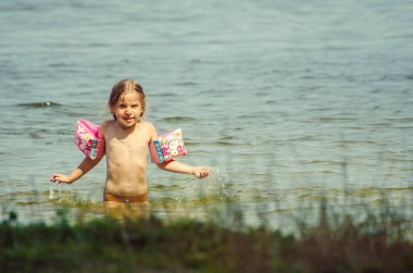 little girl learning how to swim in the lake 