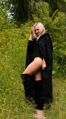 Siyah pelerinli seksi sarışın kadın.