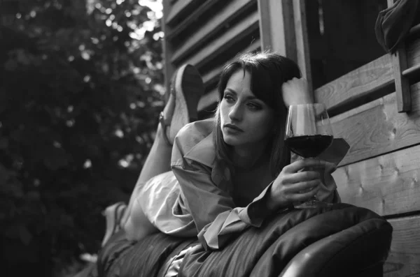 Jeune femme se détendre et boire un verre de vin rouge sur le balcon au coucher du soleil le soir . — Photo