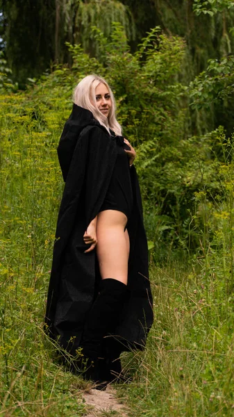 Sexy blonde woman in black cloak nature — Stock Photo, Image