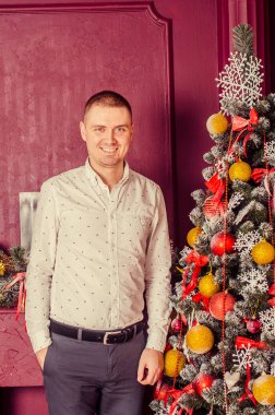 Beyaz gömlekli, Noel ağacı olan genç bir adamın portresi