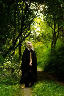 Sonbahar parkında yürüyen şık, sarışın kadın.