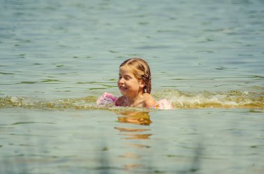 little girl learning how to swim in the lake 