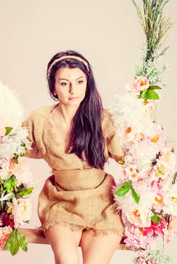 Çiçekli salıncakta oturan güzel genç bir kadın