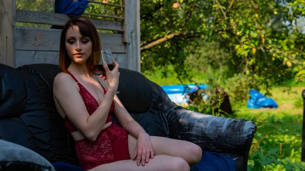 Genç bir kadın akşamüstü balkonda dinleniyor ve bir bardak kırmızı şarap içiyor.. — Stok fotoğraf