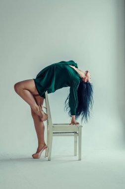 Yarı çıplak güzel bir kız klasik bir takım elbiseyle sandalyede poz veriyor..