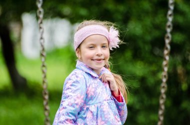 Güneşli yaz parkında oynayan 5 yaşında tatlı bir kız çocuğu. Ormanda yürüyen ve atlayan mutlu bir kız çocuğu. Çocuklar açık havada oynuyorlar..