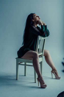 Yarı çıplak güzel bir kız klasik bir takım elbiseyle sandalyede poz veriyor..
