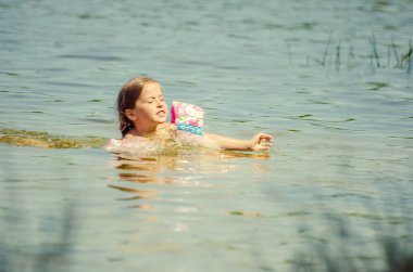 little girl learning how to swim in the lake 