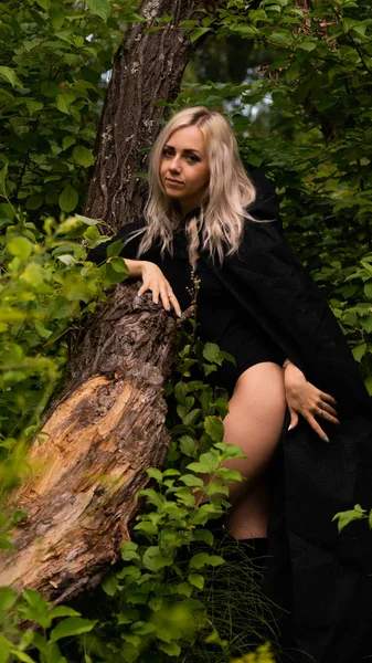 Sexy blonde vrouw in zwart mantel natuur — Stockfoto