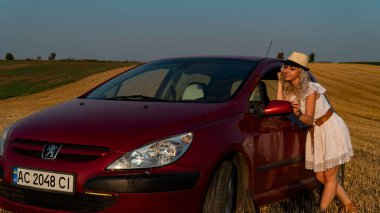 Güzel seksi sarışın kadın, kırmızı araba, tarla