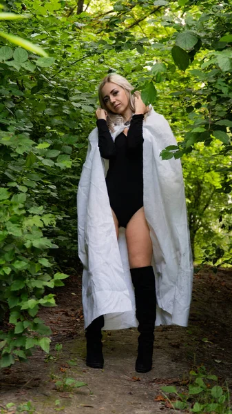 sexy blonde woman in white cloak at nature