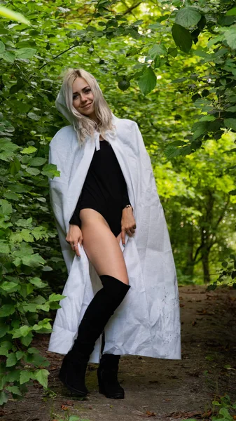 sexy blonde woman in white cloak at nature