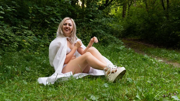 Mooie sexy blonde vrouw, het beeld van een non in een witte regenjas — Stockfoto