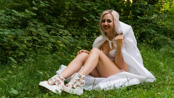 Mooie sexy blonde vrouw, het beeld van een non in een witte regenjas — Stockfoto