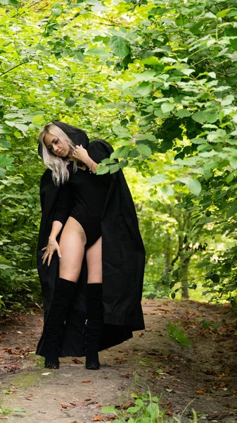 Sexy blonde woman in black cloak nature — Stock fotografie