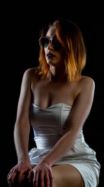 Beyaz elbiseli ve güneş gözlüklü güzel bir kadın. 