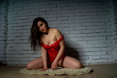 Güzel esmer kadın kırmızı arka planda kırmızı iç çamaşırlarıyla poz veriyor. Stüdyoda kırmızı elbiseli esmer kadın. Formda bir kız. Güzellik, moda ve tarz kavramı. Sevgililer Günü.