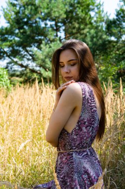 Gölün oradaki tahta iskelede poz veren siyah saçlı kadın. Sırtı Neusiedl Gölü 'nün tahta yaya köprüsüne dönmüş bir kadın. Arka plandaki kayıkhanede güneş yansımaları.