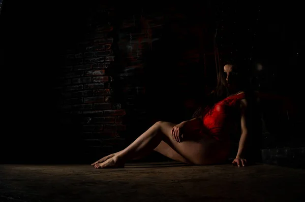 Mooie brunette vrouw poseren in rode lingerie op rode achtergrond. Brunette vrouw poseert in rood bodysuit in de studio. Fit sportief meisje. Concept van schoonheid, mode en stijl. Valentijnsdag. — Stockfoto