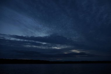Sabahın erken saatlerinde gölün üzerinde sonsuz karanlık gökyüzü manzarası.  