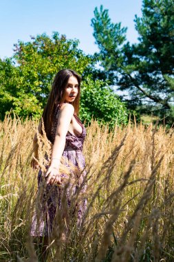 Gölün oradaki tahta iskelede poz veren siyah saçlı kadın. Sırtı Neusiedl Gölü 'nün tahta yaya köprüsüne dönmüş bir kadın. Arka plandaki kayıkhanede güneş yansımaları.