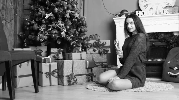 Sexy belle fille aux cheveux bruns épais luxueux dans une jupe noire avec une boîte-cadeau sur le fond de l'arbre de Noël. Séance photo du Nouvel An — Photo