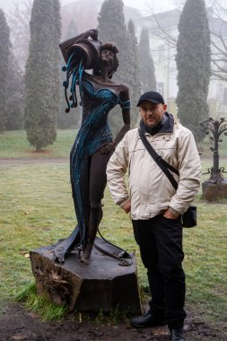 man posing with statue in park