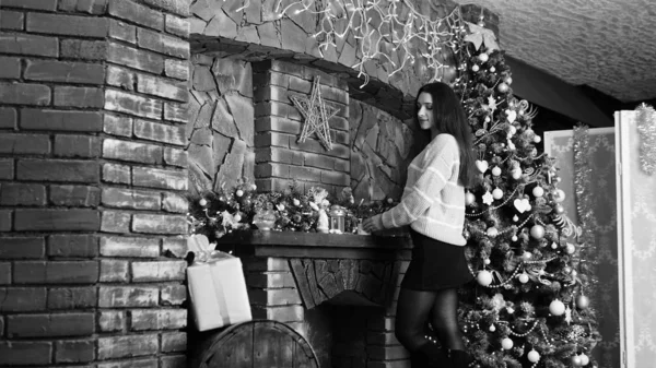 Sexy belle fille aux cheveux bruns épais luxueux dans une jupe noire avec une boîte-cadeau sur le fond de l'arbre de Noël. Séance photo du Nouvel An — Photo