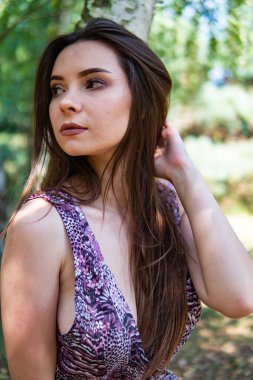 Gölün oradaki tahta iskelede poz veren siyah saçlı kadın. Sırtı Neusiedl Gölü 'nün tahta yaya köprüsüne dönmüş bir kadın. Arka plandaki kayıkhanede güneş yansımaları.