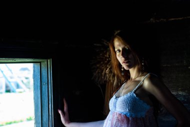 Kırsal kesimdeki evde kameraya poz veren çekici genç bir kadın.