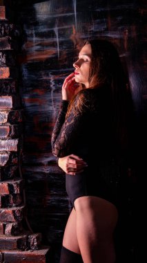 Siyah elbiseli genç bir kadın koyu bir arka planda poz veriyor, siyah saçlı ve kaslı bir spor figürü.