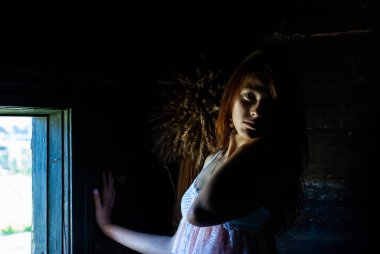 Kırsal kesimdeki evde kameraya poz veren çekici genç bir kadın.