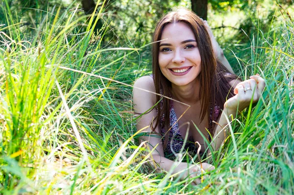 Dunkelhaarige Frau posiert am Holzsteg am See. Frau im Sommeroutfit mit dem Rücken zur hölzernen Fußgängerbrücke des Neusiedler Sees. Sonnenreflexe am Bootshaus im Hintergrund. — Stockfoto