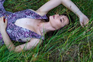 Gölün oradaki tahta iskelede poz veren siyah saçlı kadın. Sırtı Neusiedl Gölü 'nün tahta yaya köprüsüne dönmüş bir kadın. Arka plandaki kayıkhanede güneş yansımaları.