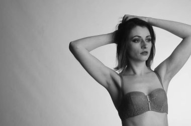 Beyaz arka planda yalnız poz veren dantelli iç çamaşırlı güzel kadın. 