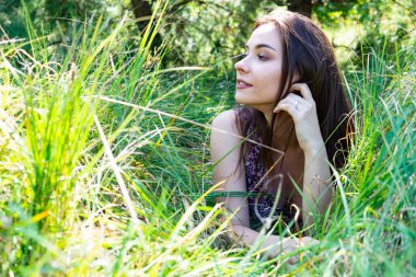 Gölün oradaki tahta iskelede poz veren siyah saçlı kadın. Sırtı Neusiedl Gölü 'nün tahta yaya köprüsüne dönmüş bir kadın. Arka plandaki kayıkhanede güneş yansımaları.