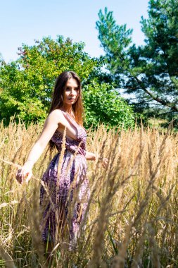 Gölün oradaki tahta iskelede poz veren siyah saçlı kadın. Sırtı Neusiedl Gölü 'nün tahta yaya köprüsüne dönmüş bir kadın. Arka plandaki kayıkhanede güneş yansımaları.