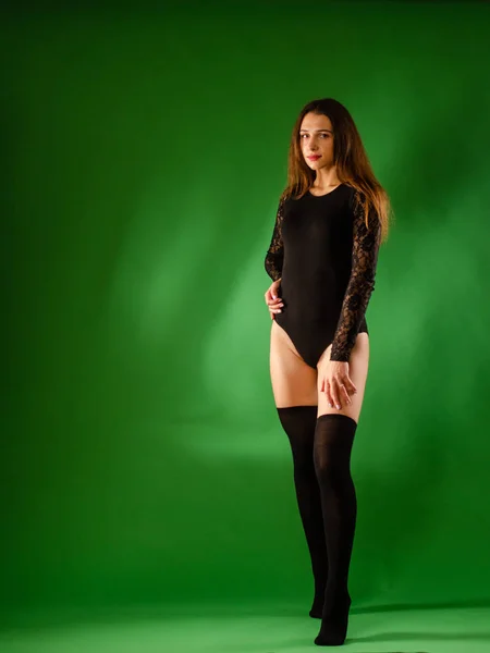 Meisje in zwart bodysuit op groene achtergrond — Stockfoto
