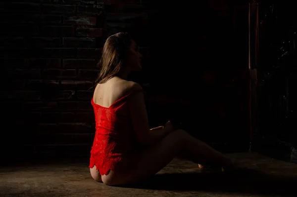 Vacker brunett kvinna poserar i röda underkläder på röd bakgrund. Brunett kvinna poserar i röd body suit i studio. Passar sportig flicka. Begreppet skönhet, mode och stil. Alla hjärtans dag. — Stockfoto