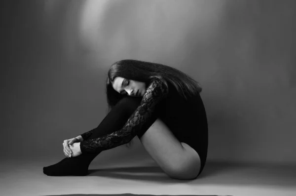 Mujer joven en un body negro posando sobre un fondo oscuro, pelo negro y una figura deportiva muscular . —  Fotos de Stock