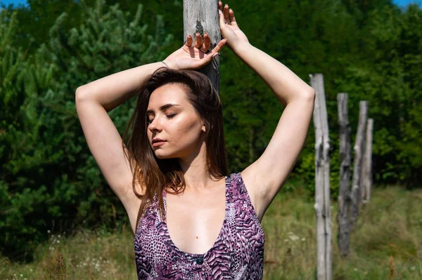 一个黑头发的女人躺在湖边的木制码头上。身穿夏装的女人背对着纽西埃尔湖的木制人行天桥。背景中船屋的阳光反射. — 图库照片