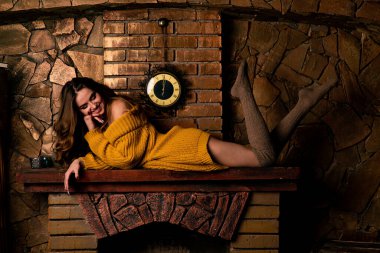 Şöminenin yanında oturan güzel kız. Noel için içi köknar dalları ve oyuncaklarla süslenmiş lüks bir iç mekan..