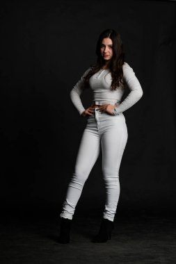 Saçları topuz şeklinde olan genç bayan kollarını kavuşturup yukarı bakıyor. Gri elbiseli, ısıran dudakları olan, arzularını düşünen kaprisli kadın manken. Hayal dünyası konsepti.