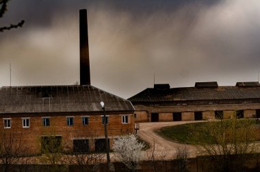 Dramatik bulutlu gökyüzü altında terk edilmiş fabrika binaları