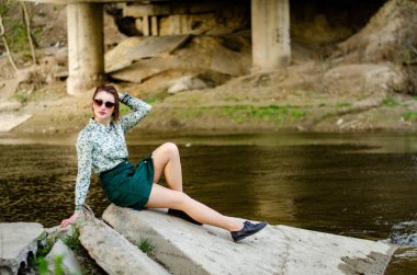 Güneşli bir günde nehir kenarında poz veren güzel çekici bir kadın. 