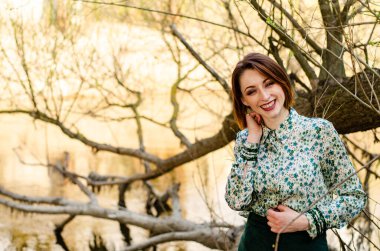 Güneşli bir günde nehir kenarında poz veren güzel çekici bir kadın. 