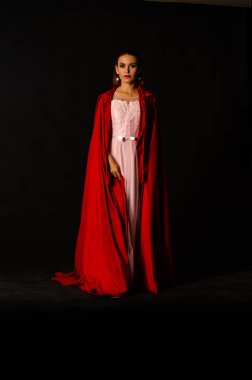 Koyu arkaplanda kırmızı pelerinli güzel bir kadın dramatik ve fantastik bir çekim 