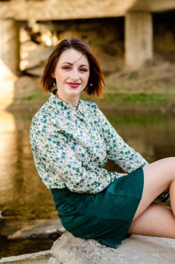 Güneşli bir günde nehir kenarında poz veren güzel çekici bir kadın. 