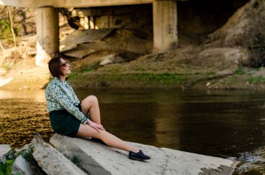 Güneşli bir günde nehir kenarında poz veren güzel çekici bir kadın. 